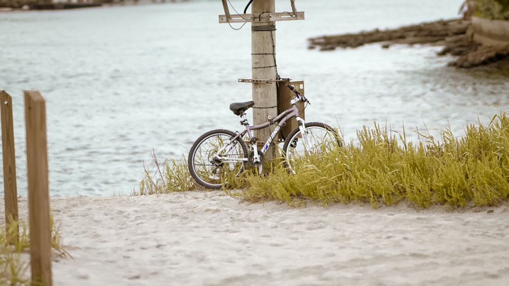 Ein Fahrrad, das neben einem Holzpfosten am Strand geparkt ist