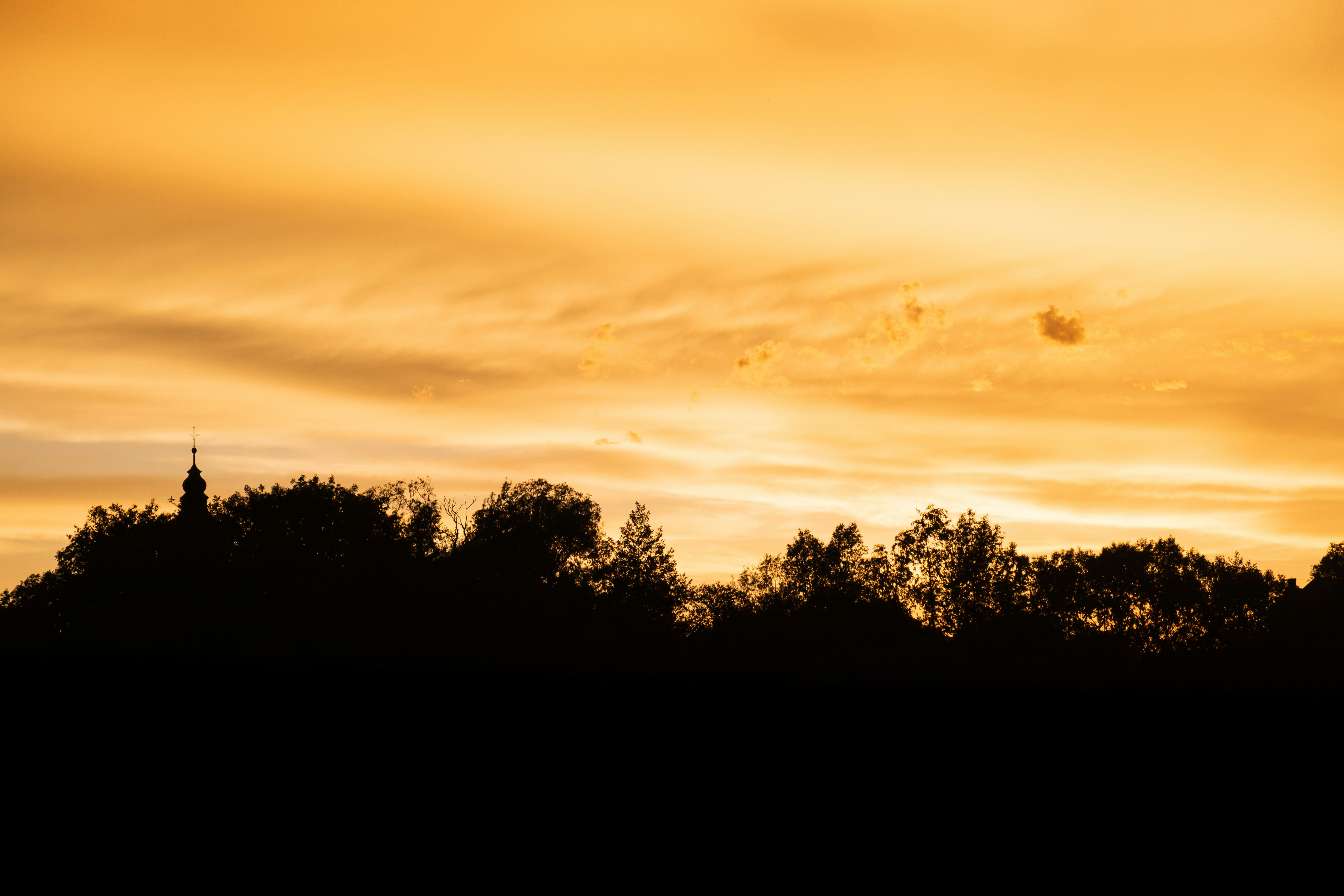 a plane flying in the sky at sunset
