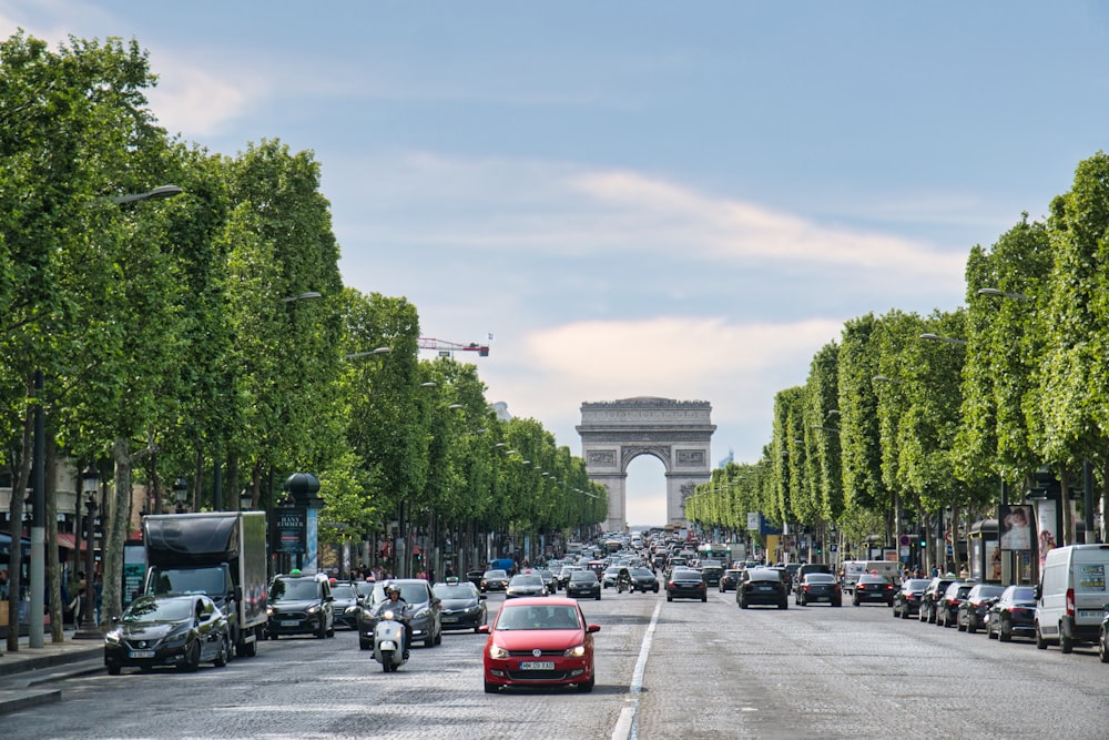 a street lined with trees and a monument in the background