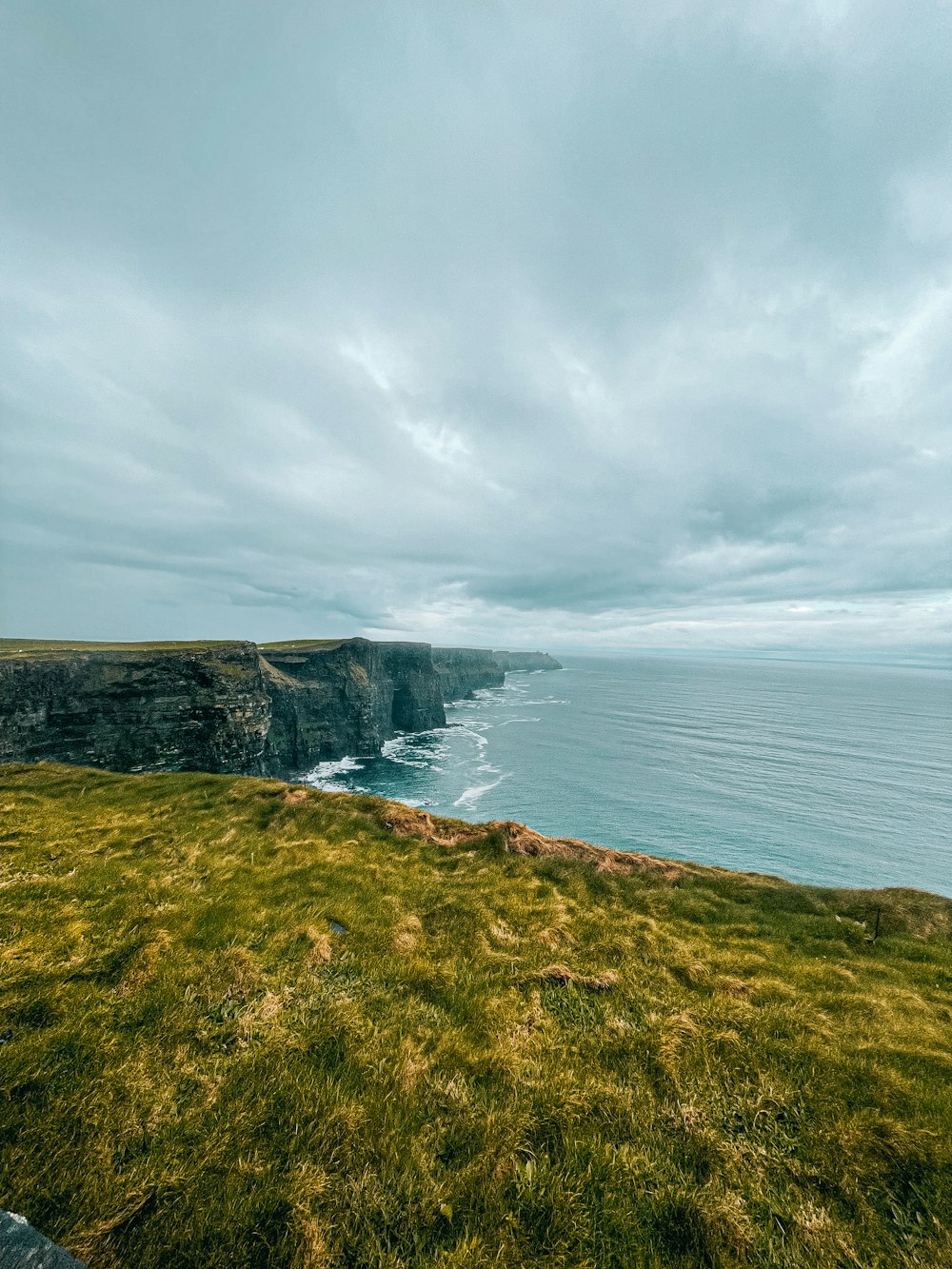 a view of the ocean from a grassy hill