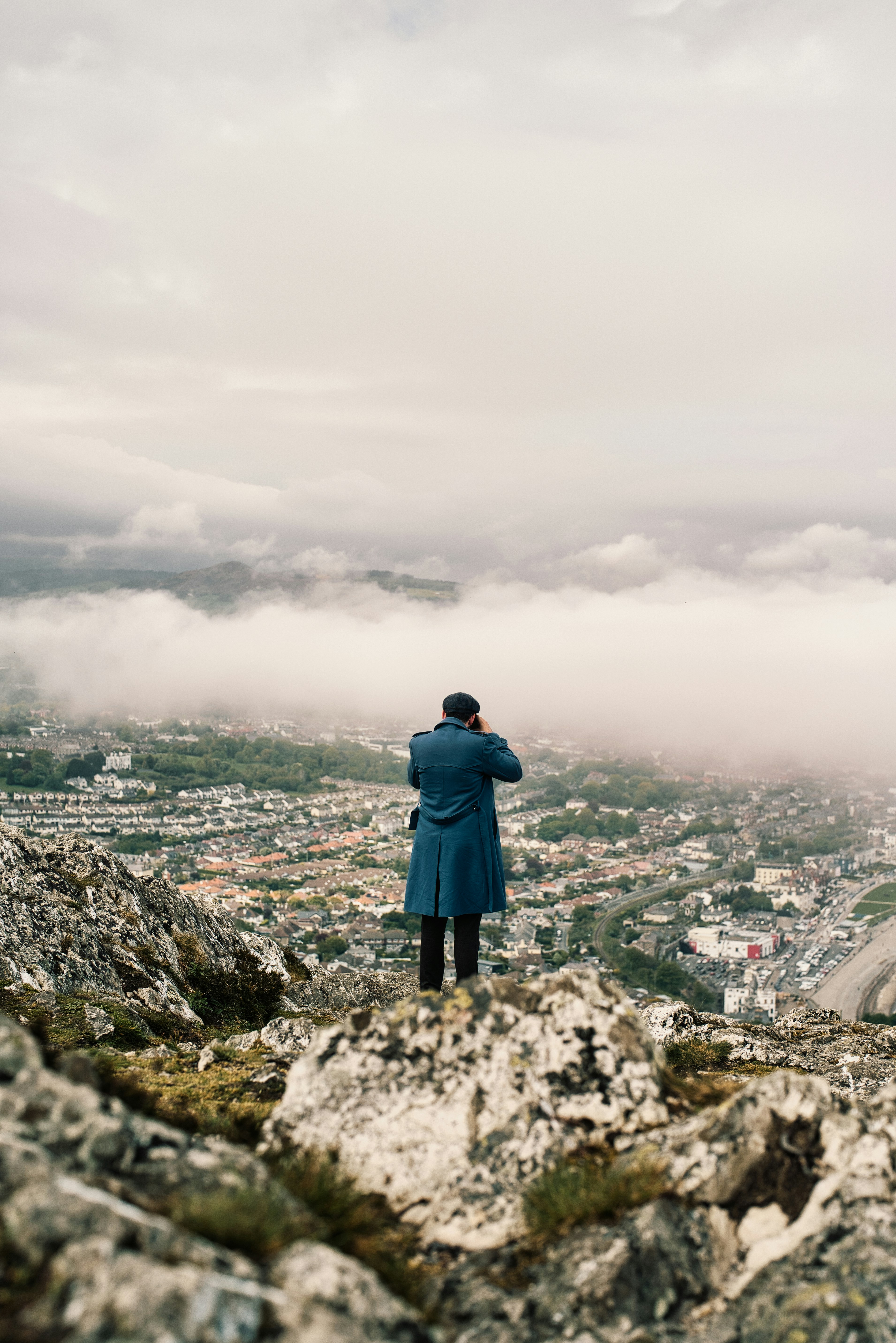 a man standing on top of a mountain looking at the clouds