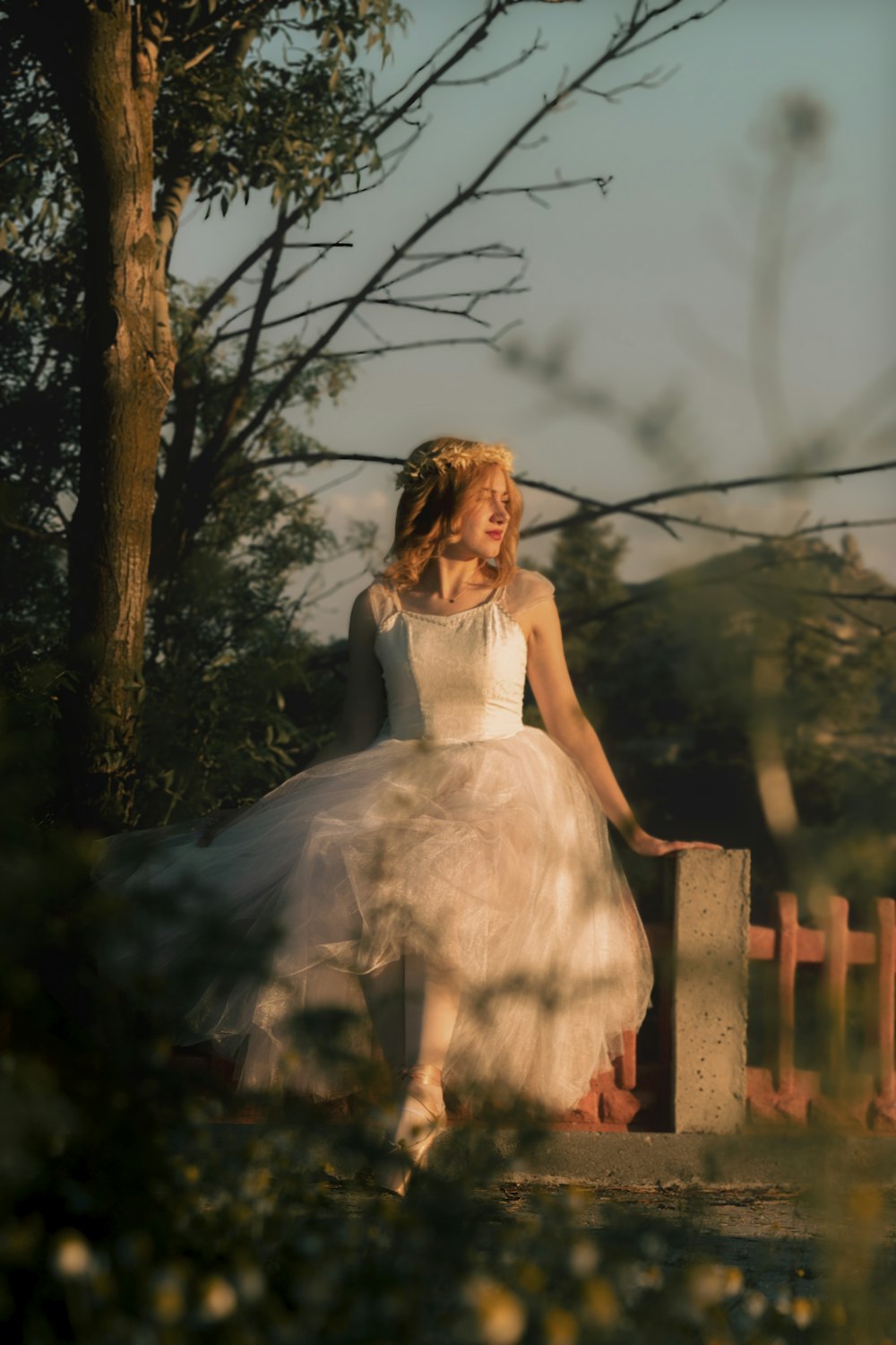 a woman in a white dress is sitting on a bench