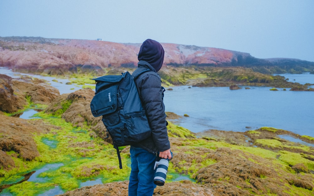 a man with a backpack is standing on a hill