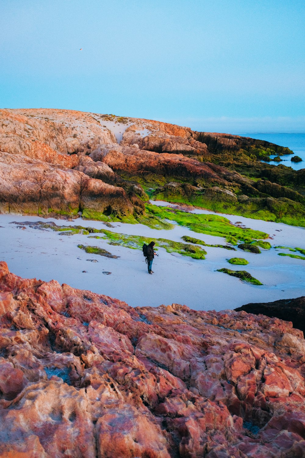 a lone person standing on a rocky beach
