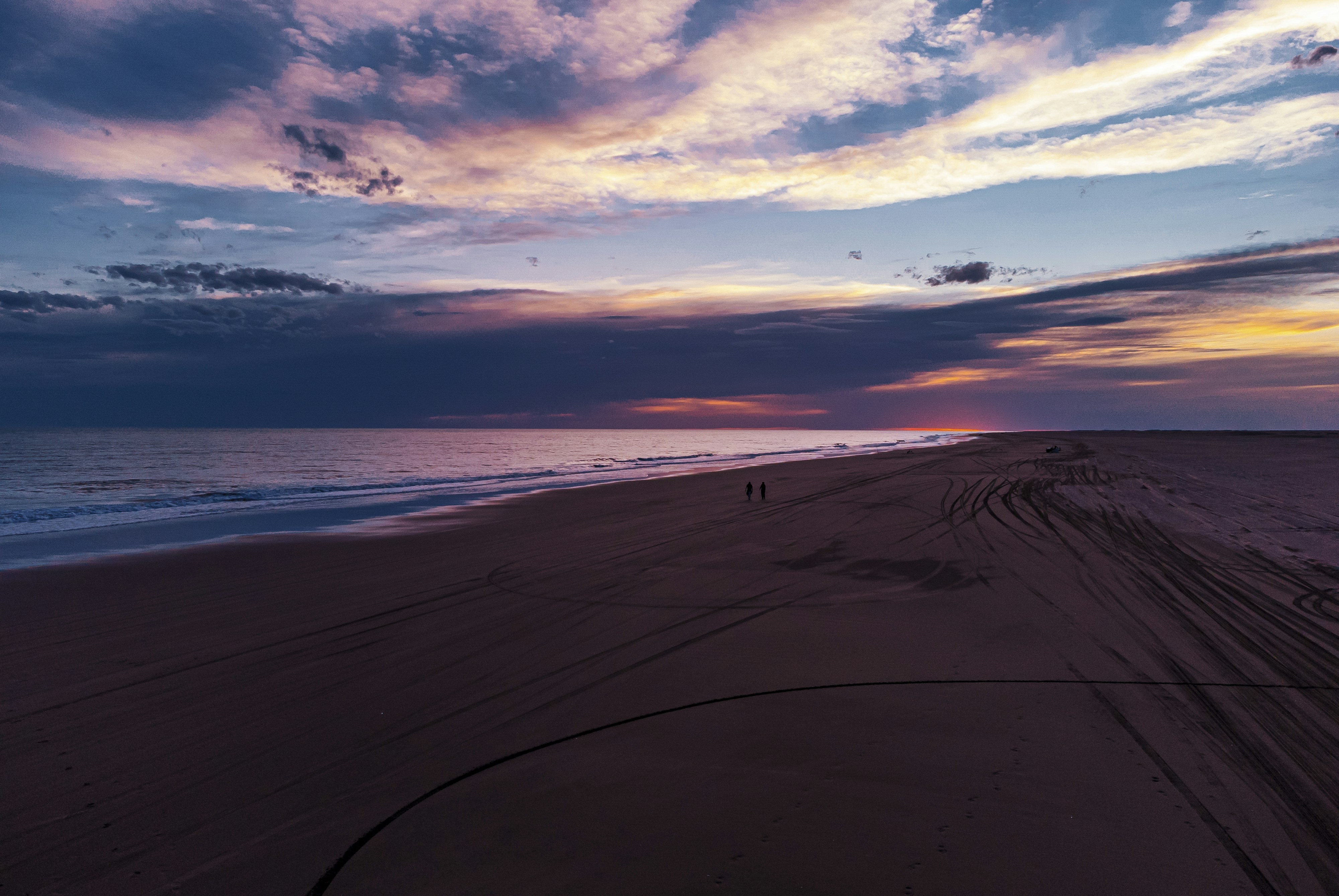 Empty nearly beach during an off-season sunset with 2 travellers