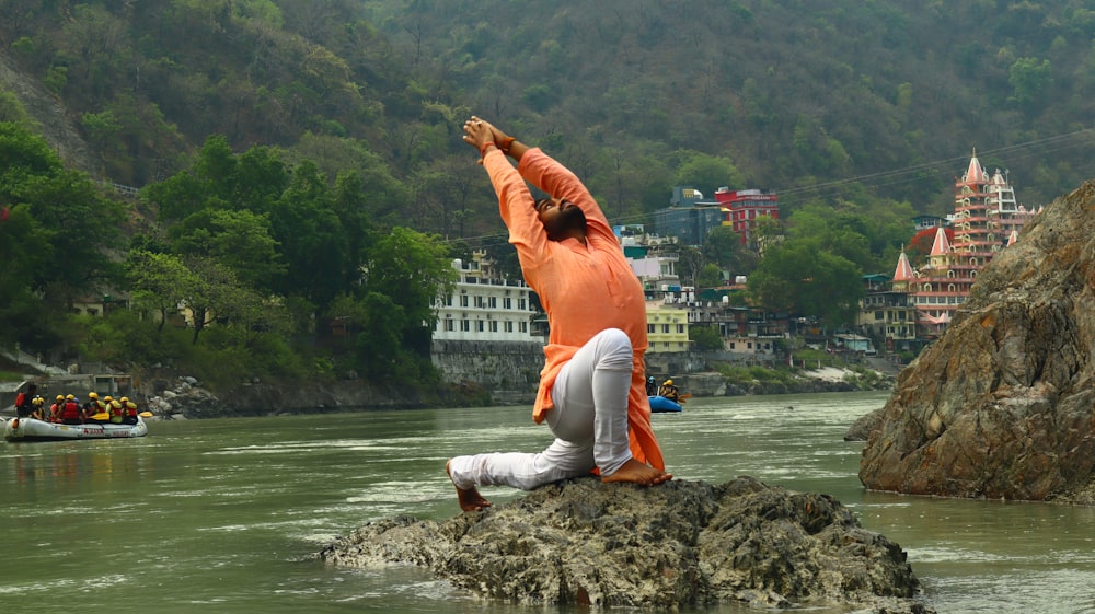 uma pessoa fazendo yoga em uma rocha no meio de um rio