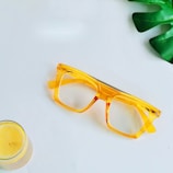 a pair of yellow glasses next to a glass of orange juice