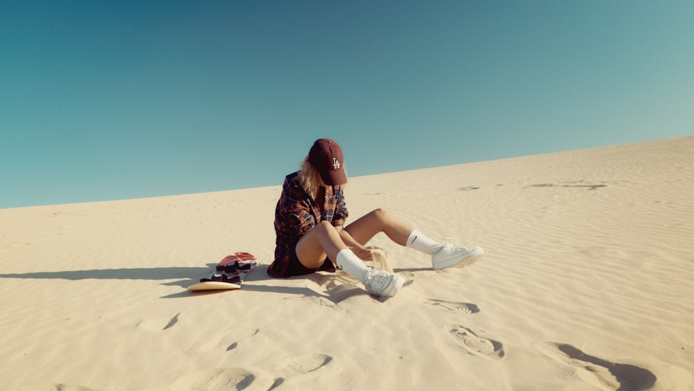 Una mujer sentada en la cima de una playa de arena