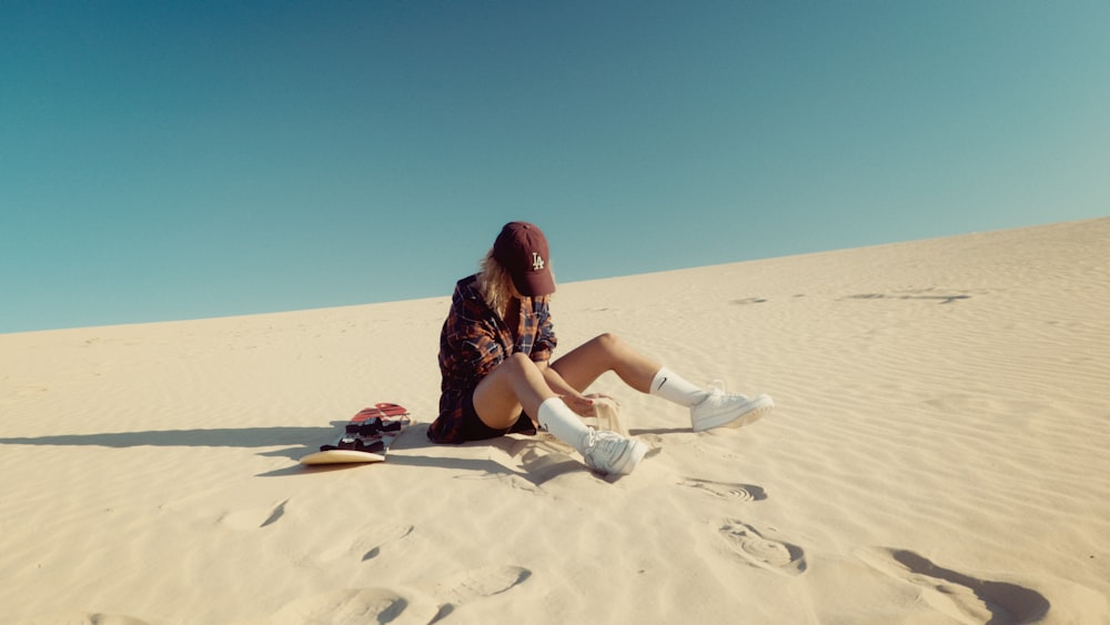 a woman sitting on top of a sandy beach