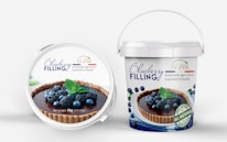 A pair of containers with blueberry filling. The front lid displays an image of a tart topped with blueberries and blackberries, garnished with mint leaves. The brand name 'Fil d'OR' is visible, promoting sustainable agriculture and quality. The larger bucket offers a similar design with additional text highlighting 'all natural ingredients' and the net weight of 6kg (13.4 lbs).