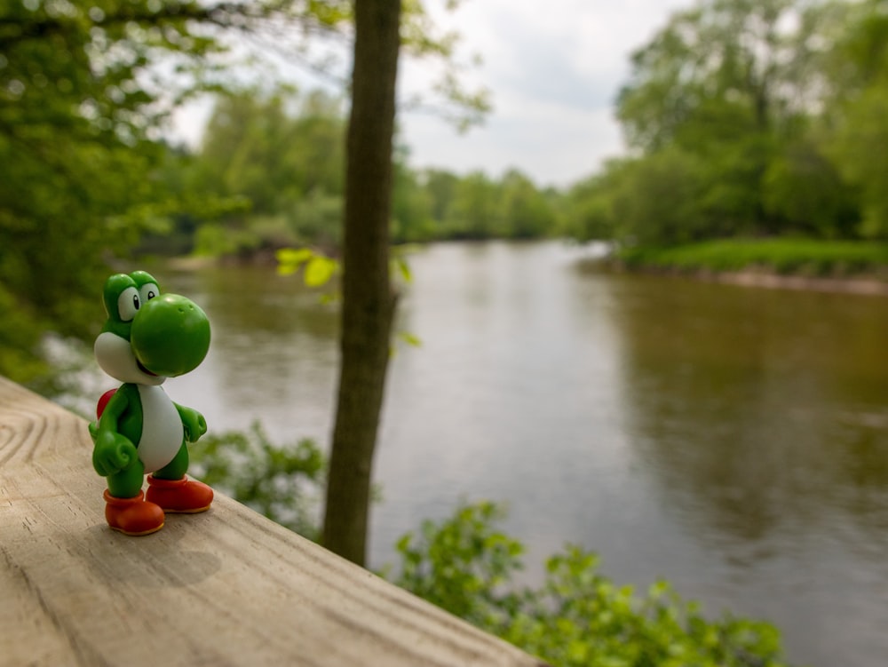 a toy figure is sitting on a ledge near a river