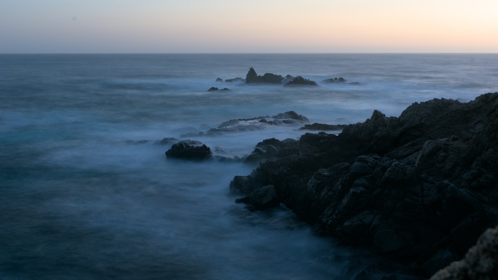 a body of water with rocks in the foreground