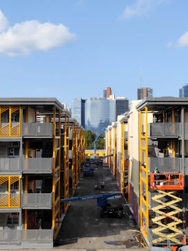 Construction workers collaborating on a modern apartment complex in a revitalized urban area.