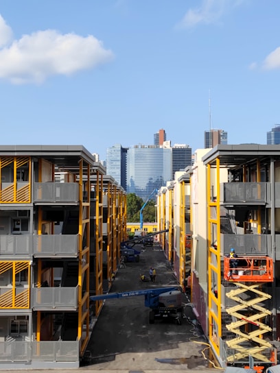 A modern apartment building under construction with cranes and workers on site.