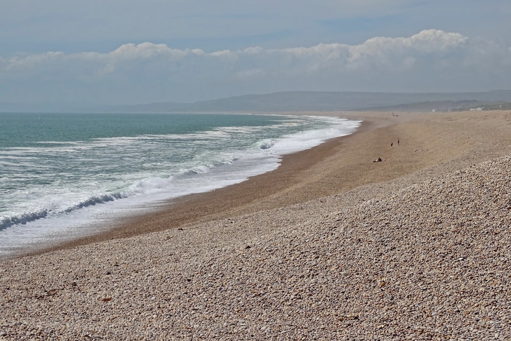 Una playa con pocas personas caminando por ella