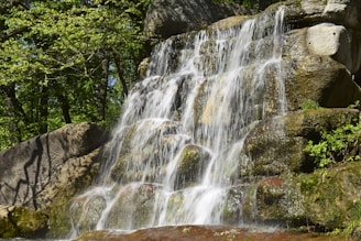 A serene backyard waterfall flowing over natural-looking stones.