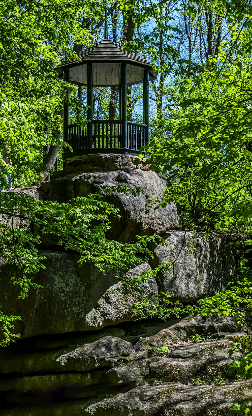 a gazebo sitting on top of a rock covered hillside