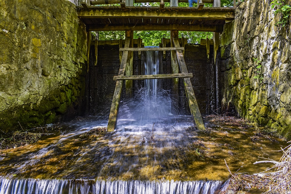 a wooden bridge over a small waterfall in a forest