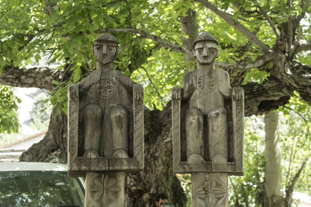 a couple of statues sitting next to a tree
