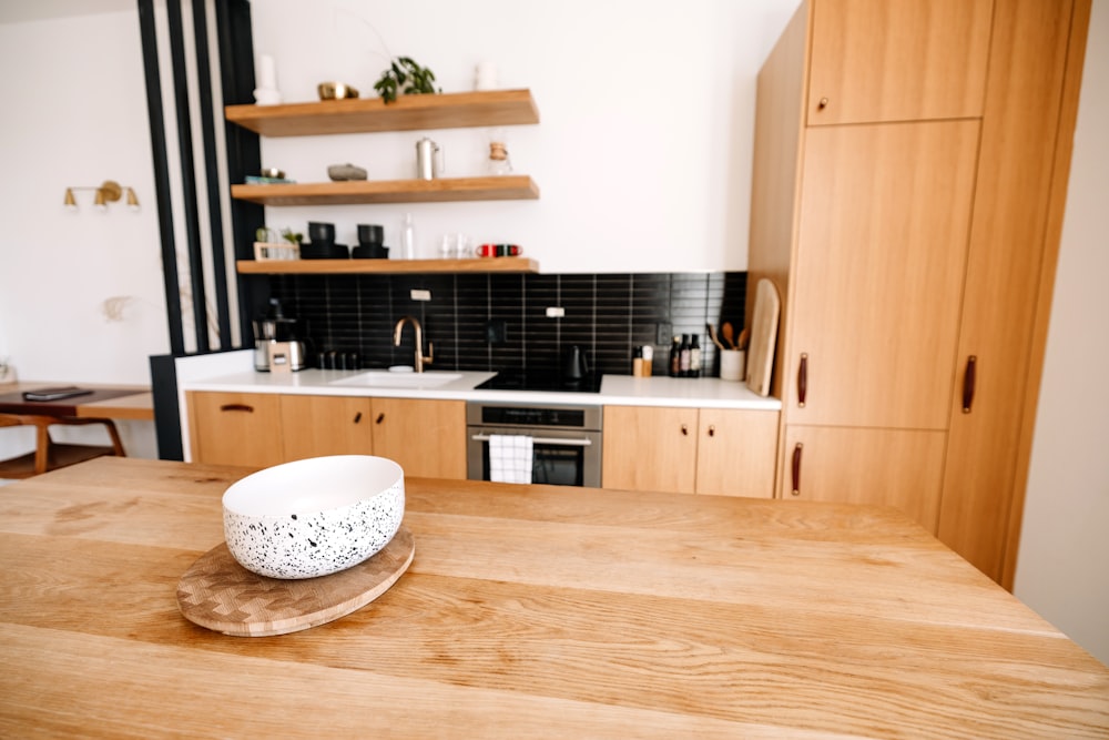 a bowl sitting on a wooden table in a kitchen