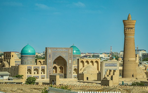 مدرسه‌ی میرعرب با دو گنبد فیروزه‌ای و مناره‌ی آجری کلان در بخارا