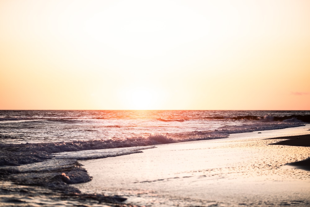 a man walking across a beach next to the ocean