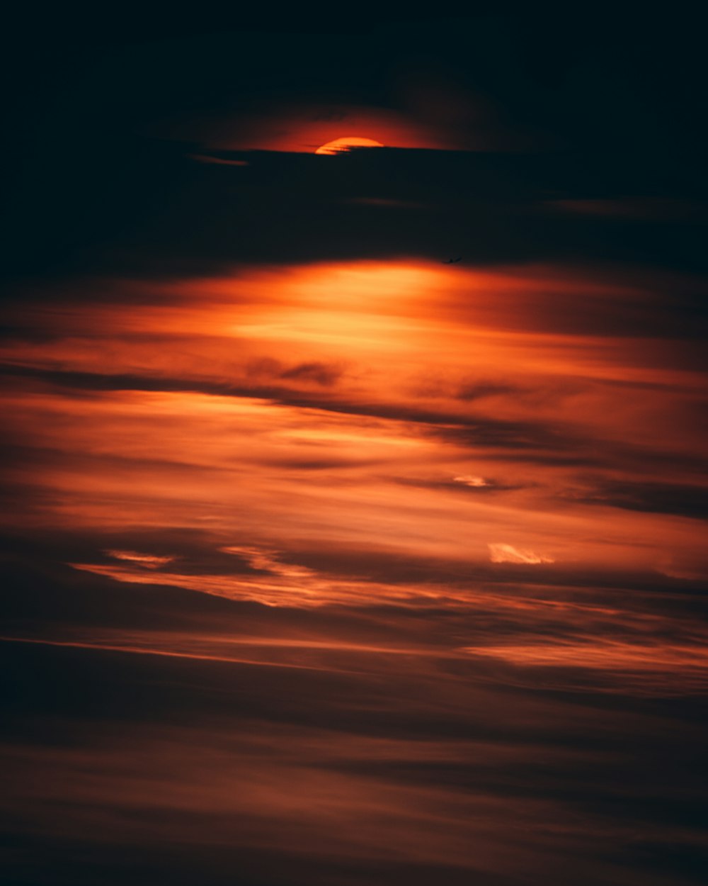 a plane flying in the sky with the sun in the background