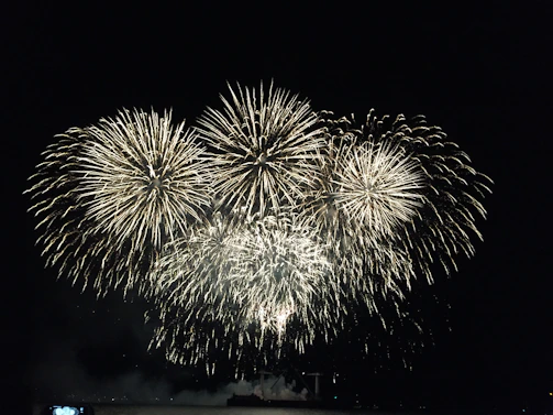 A spectacular fireworks display lighting up the night sky with colorful bursts over a grand 3D mega stage.