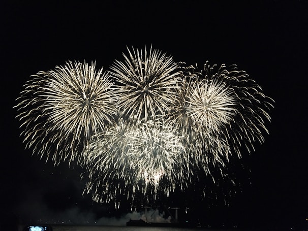 A night scene showing a grand fireworks finale with multiple colors exploding in the sky.