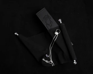 A sleek black blindfold resting beside a set of metal restraints on a wooden table.