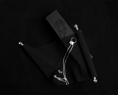 A sleek black blindfold resting beside a set of metal restraints on a wooden table.