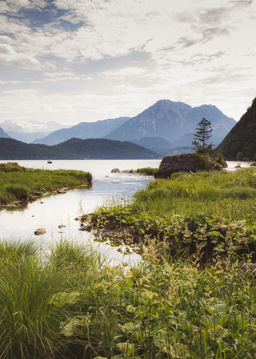 a body of water surrounded by mountains and grass