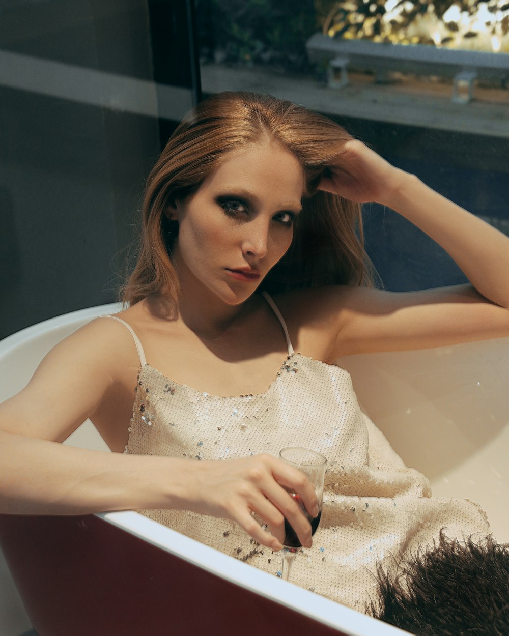 a woman sitting in a bathtub with her hair in her hand