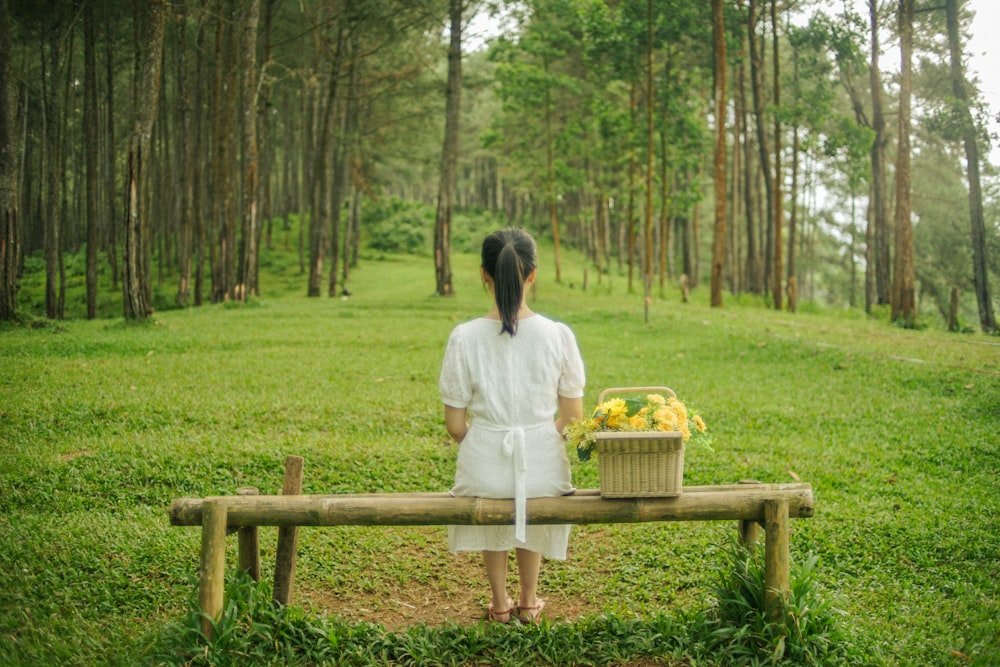 a woman sitting on a bench with a basket of flowers