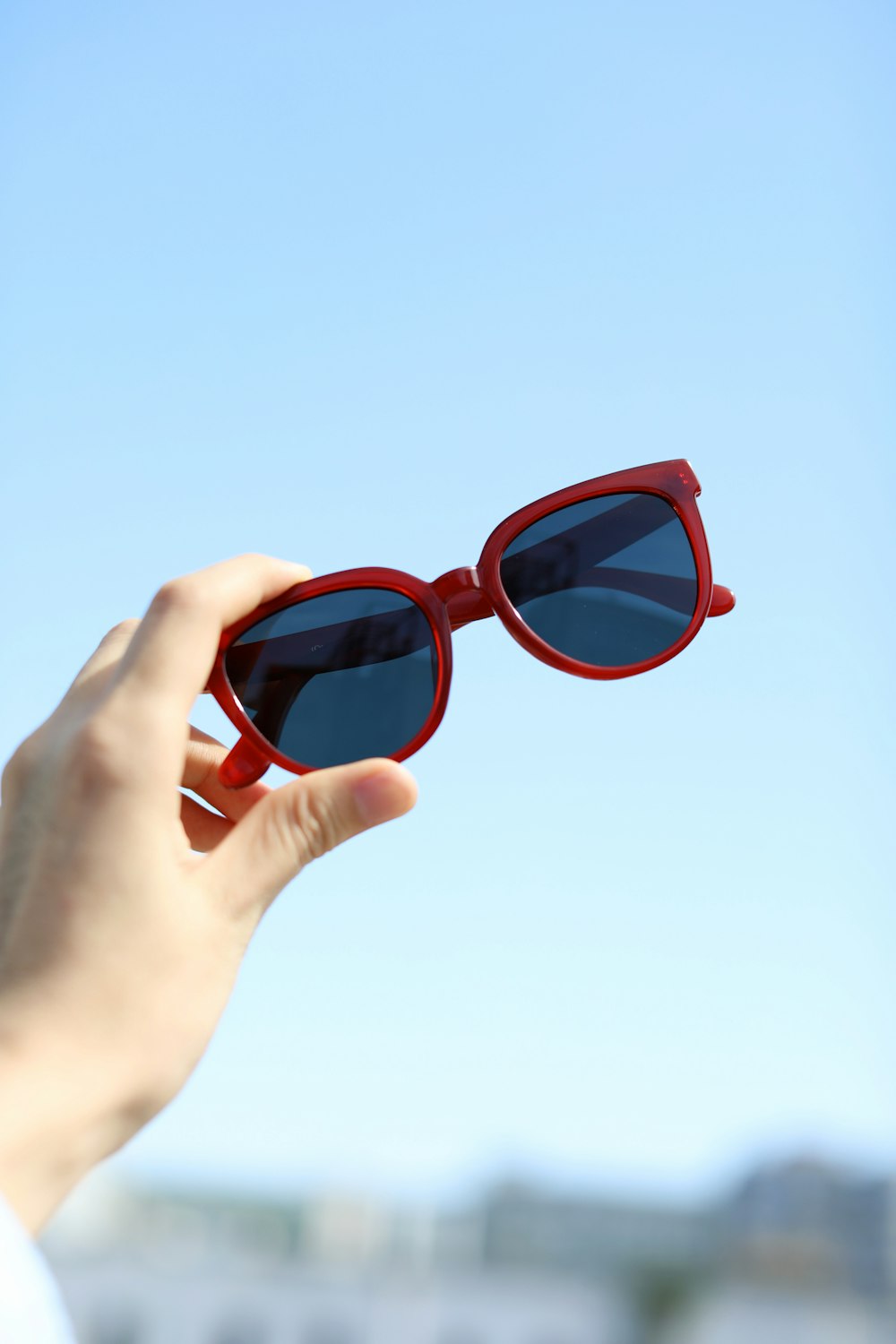 a person holding up a pair of red sunglasses