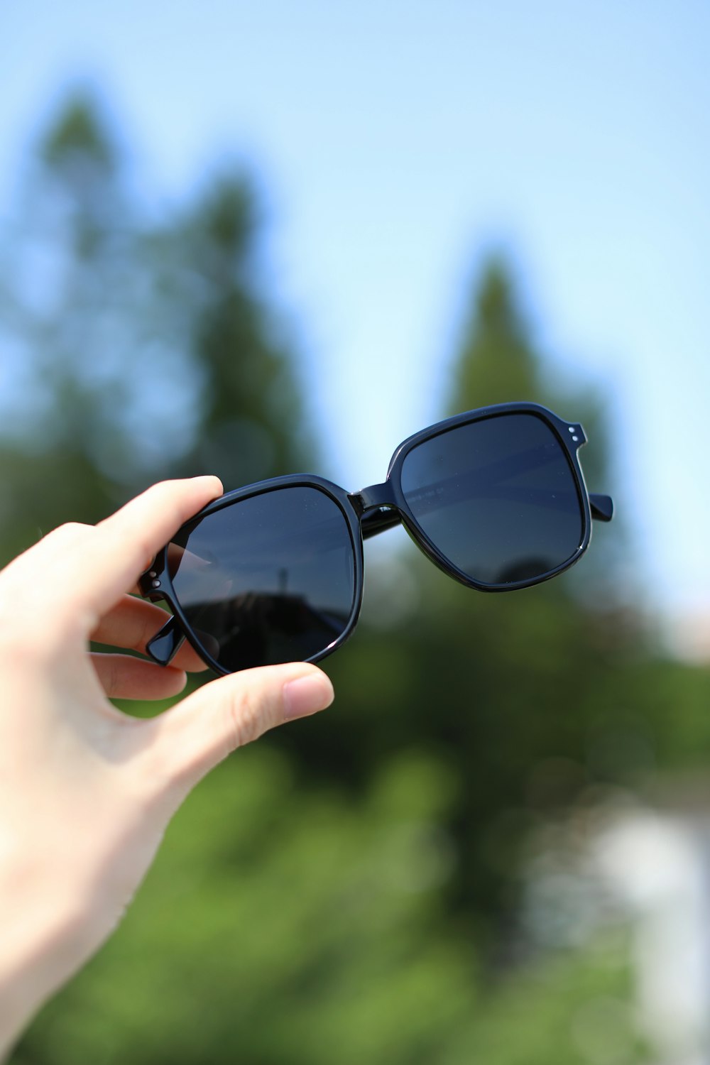 a person holding a pair of sunglasses in their hand