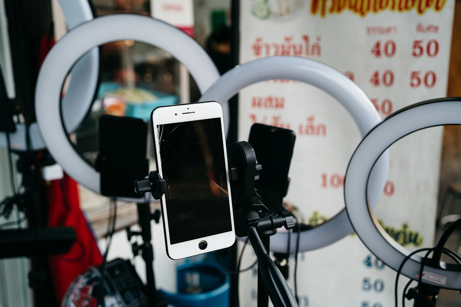 Smartphones mounted on tripods in front of ring lights, set up for livestreaming