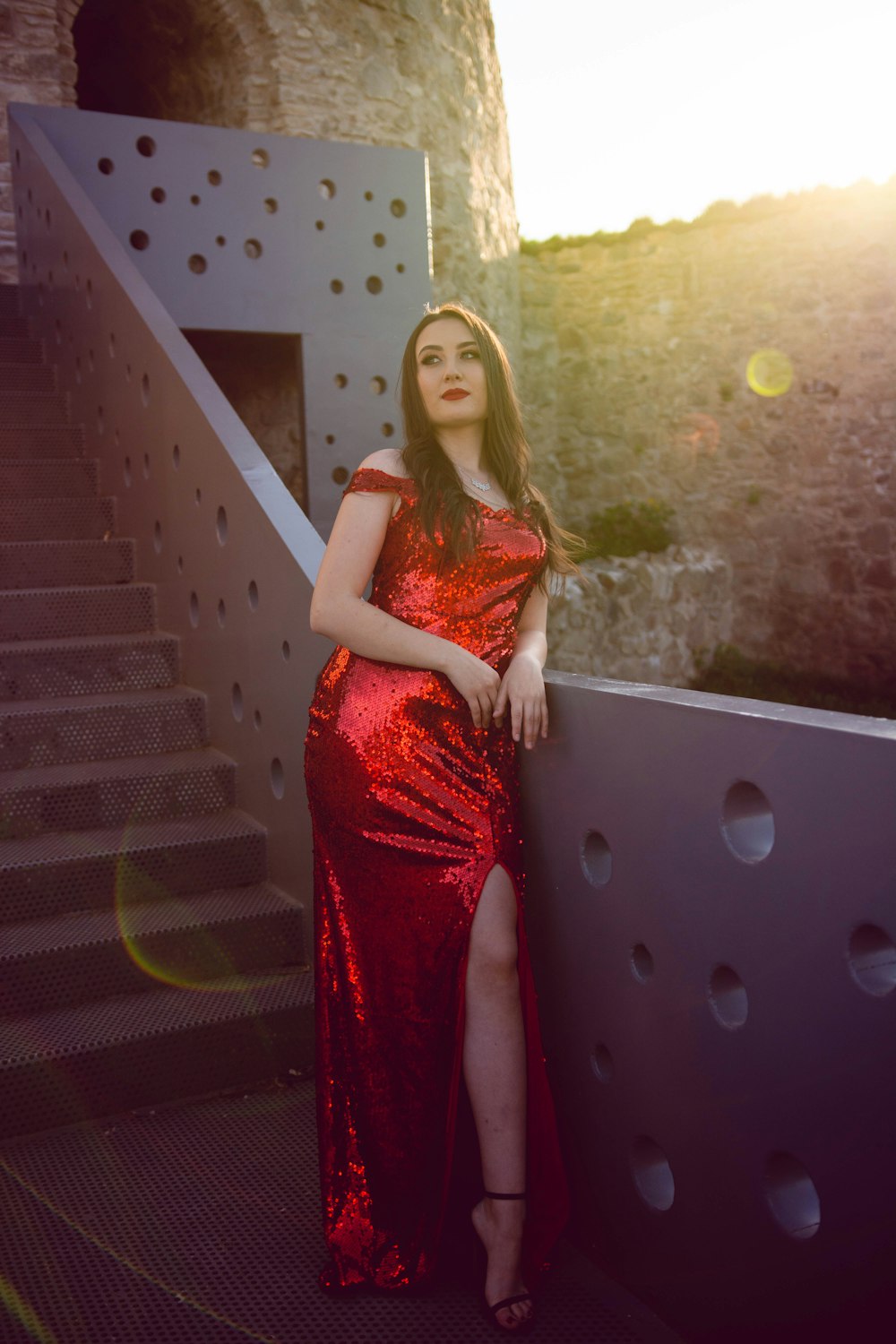 a woman in a red dress leaning against a wall