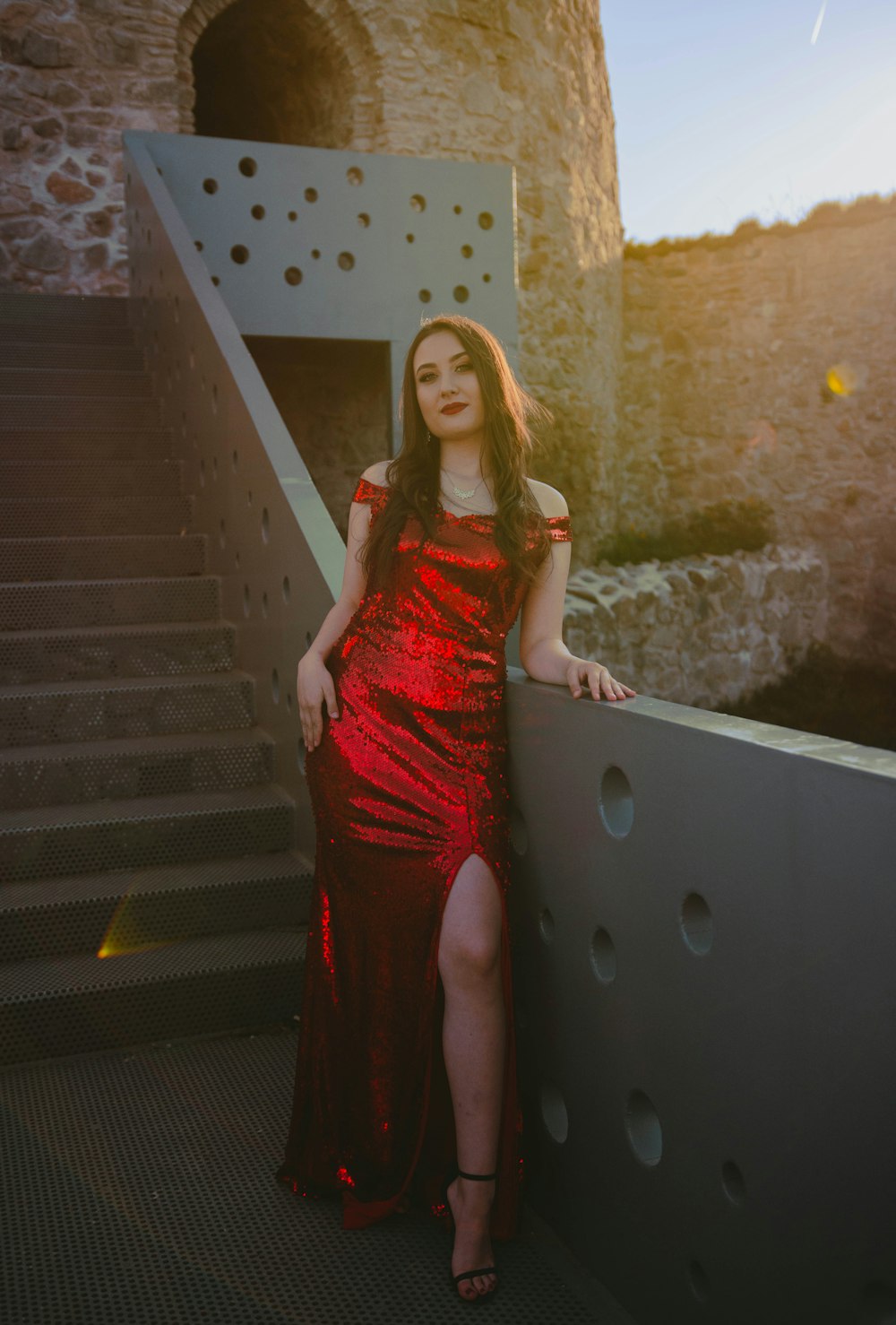 a woman in a red dress leaning against a wall