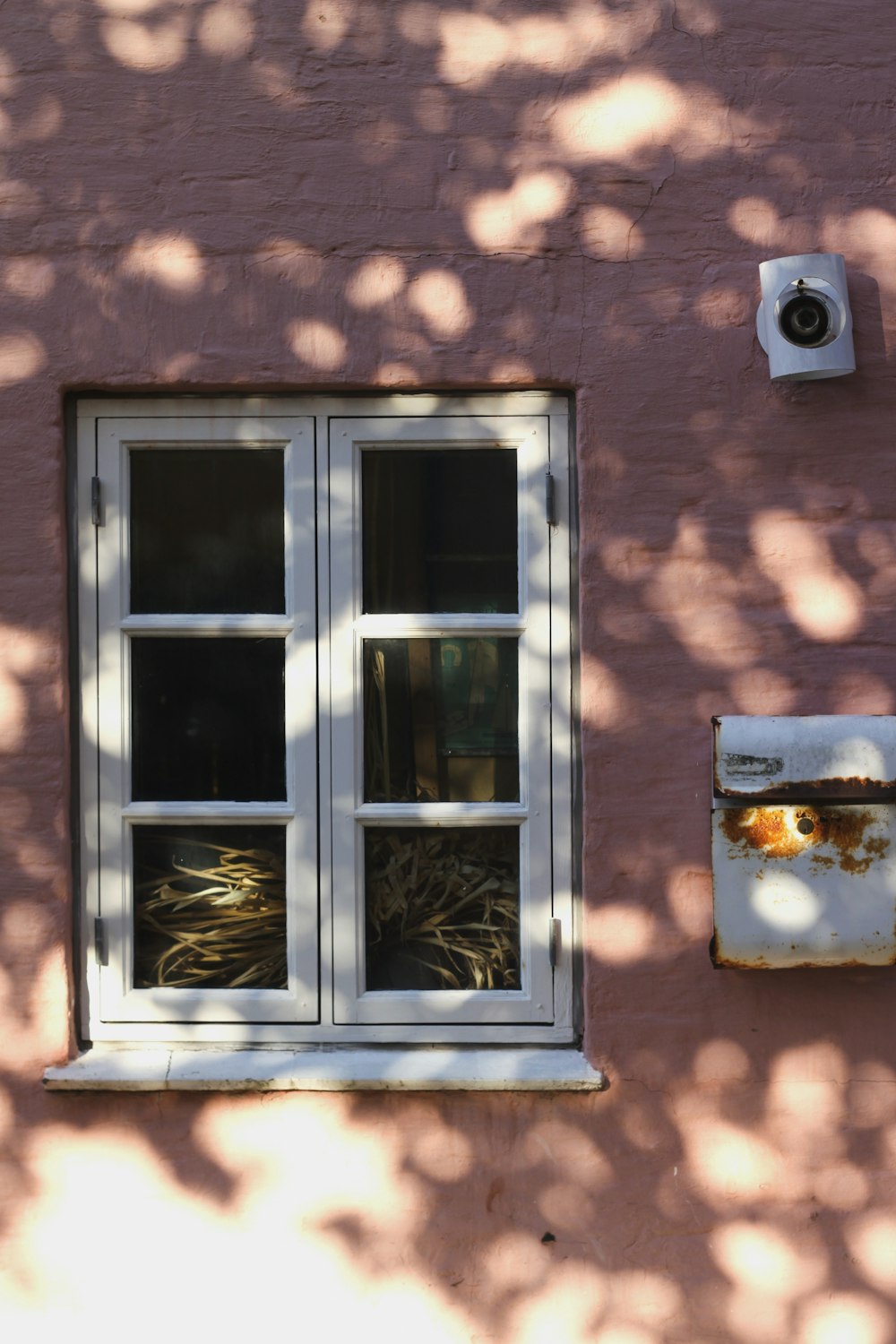 a pink building with a window and a bird feeder