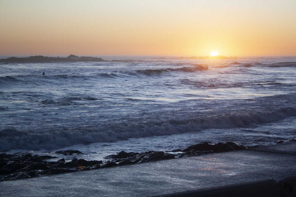 the sun is setting over the ocean waves