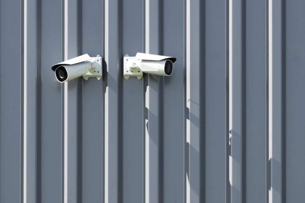 Two security cameras mounted on a metal wall