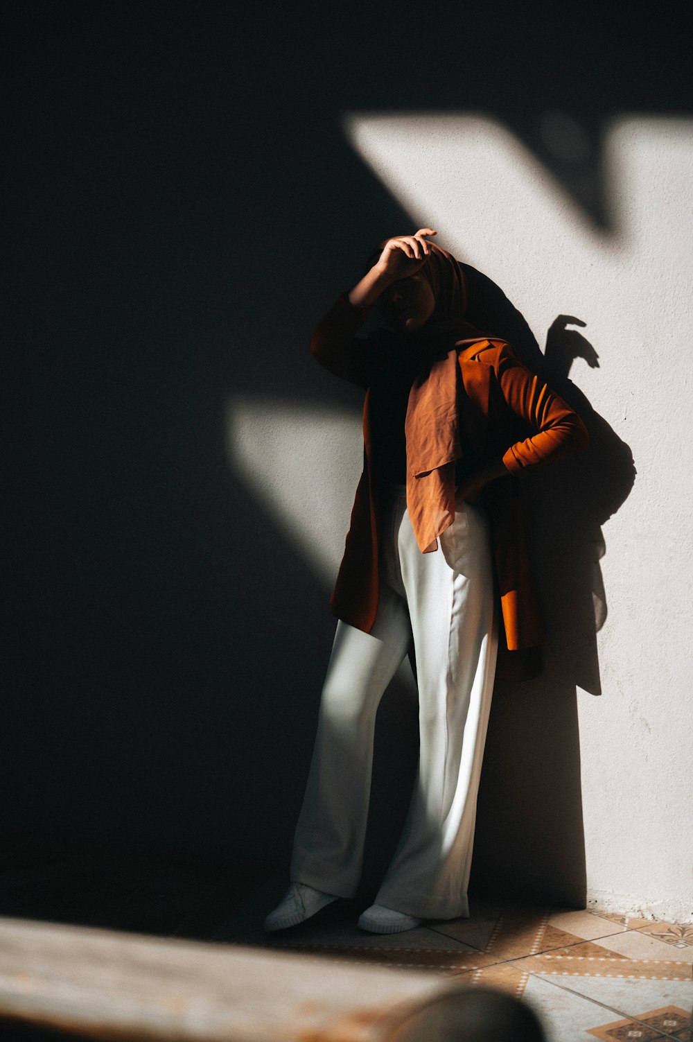 a woman standing against a wall with her hands on her head