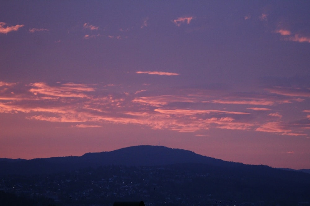 a view of a mountain at sunset with clouds in the sky