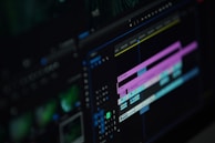A close-up of a computer screen displaying a video editing software interface with multiple timeline tracks in purple and blue, knobs, and various editing tools visible.