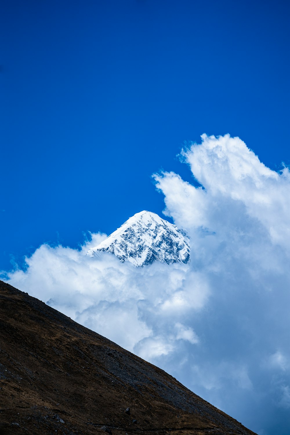 a snow covered mountain in the middle of a cloud filled sky