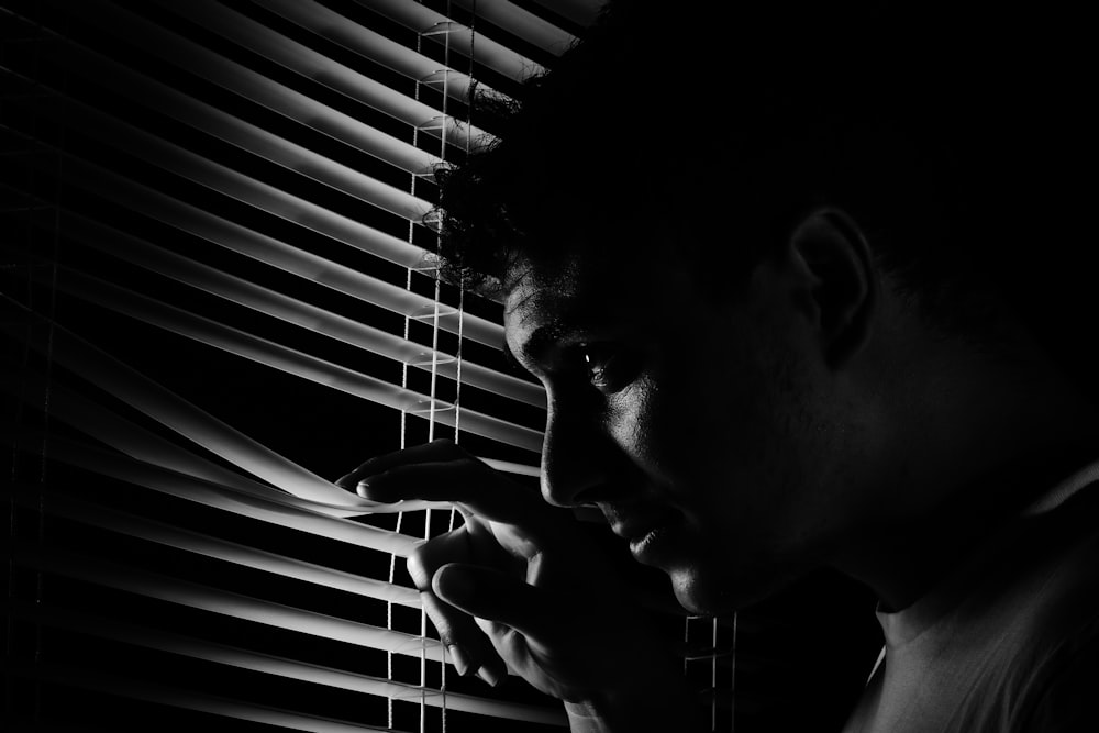 a black and white photo of a man looking out a window