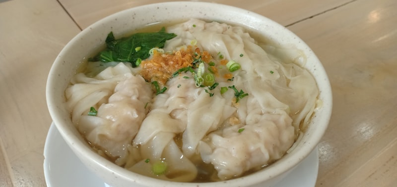 A white bowl filled with tiny hand pinched dumplings