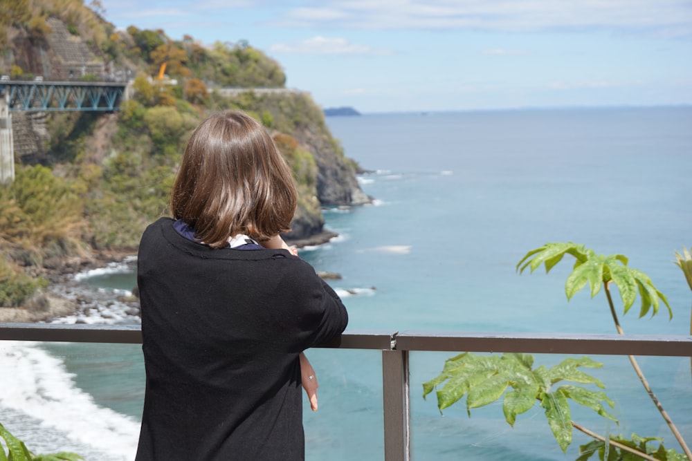 a woman standing on a balcony looking out at the ocean