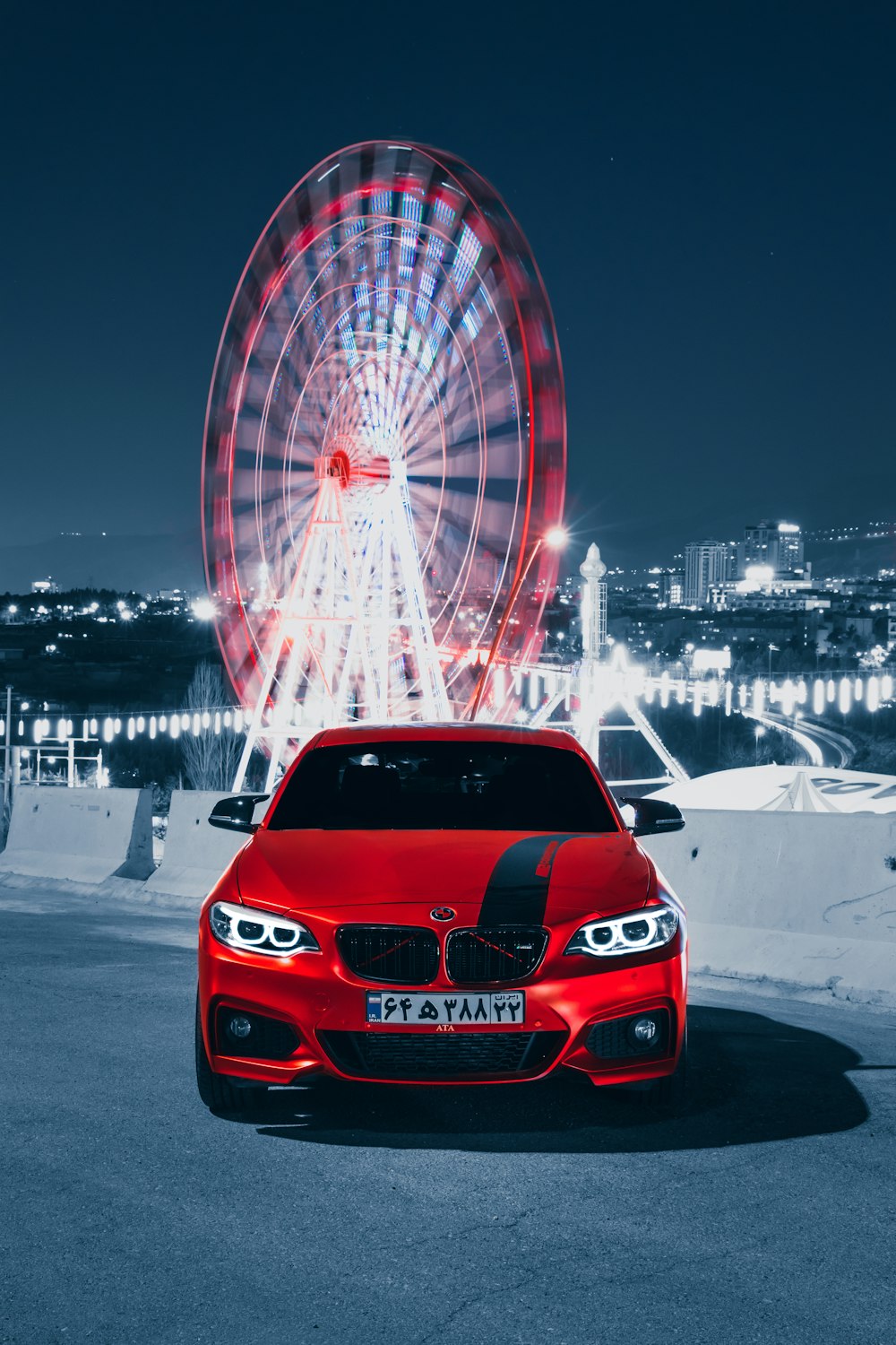 a red car parked in front of a ferris wheel